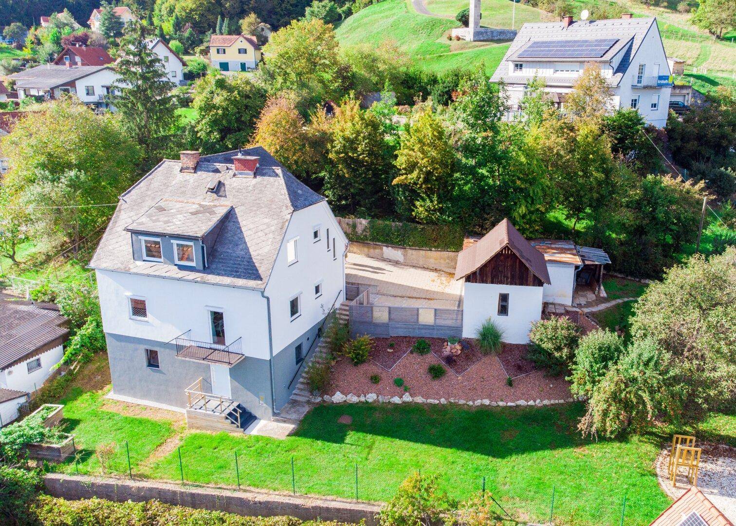 Luftaufnahme des Anwesens mit Hauptgebäude, Nebengebäude und weitläufigem Gartenbereich.
