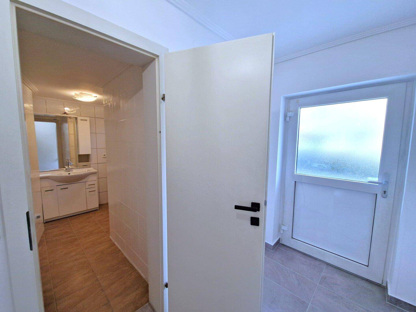 Eingangsbereich mit Fliesenboden und offener Tür zu einem Badezimmer.