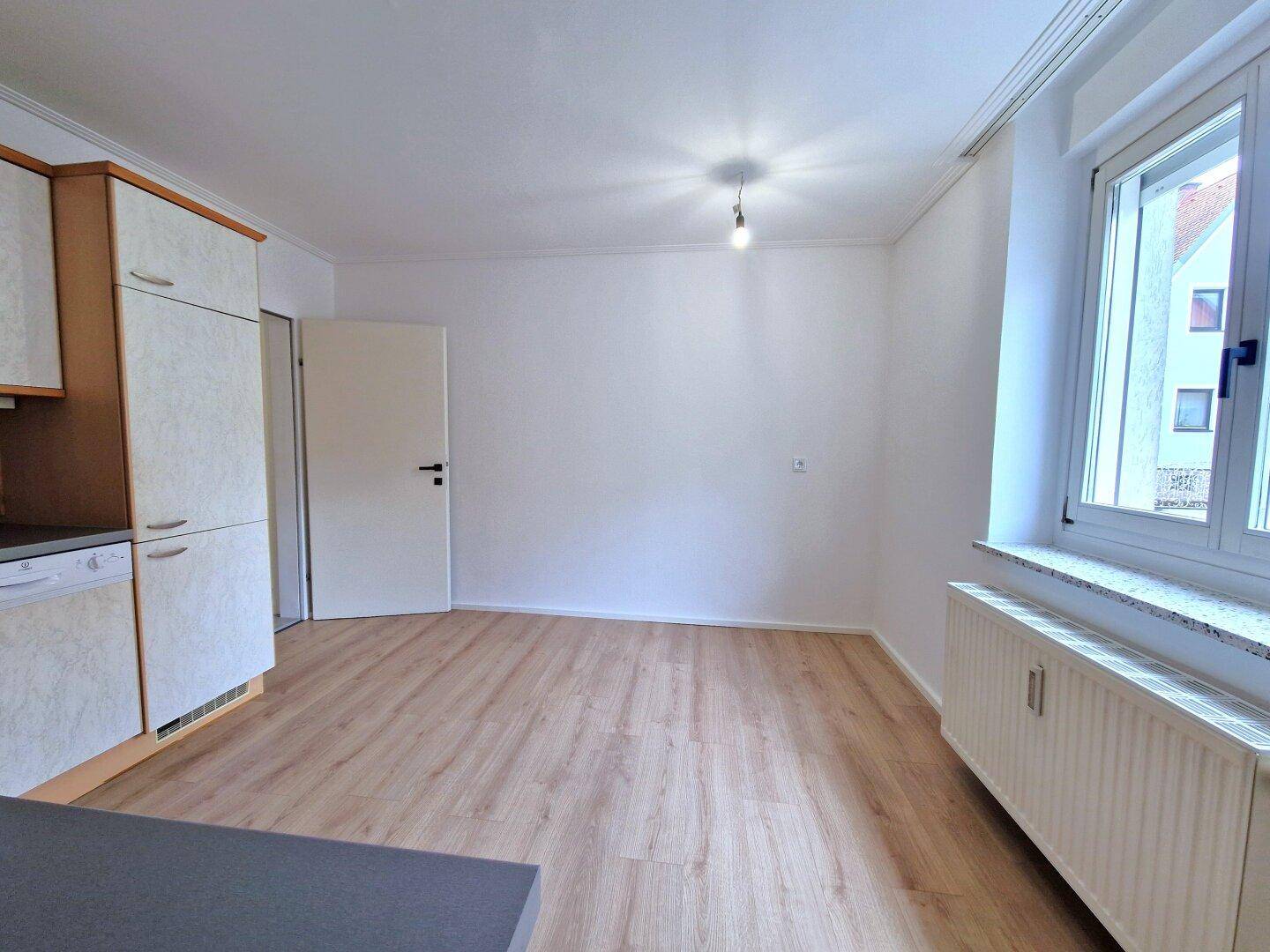 Helle Küche mit Einbauküche, Fenster und Platz für einen Essbereich.