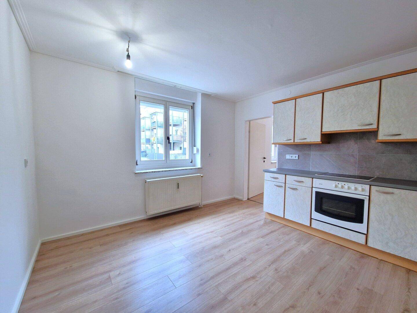 Helle Küche mit Einbauküche, Fenster und Platz für einen Essbereich.
