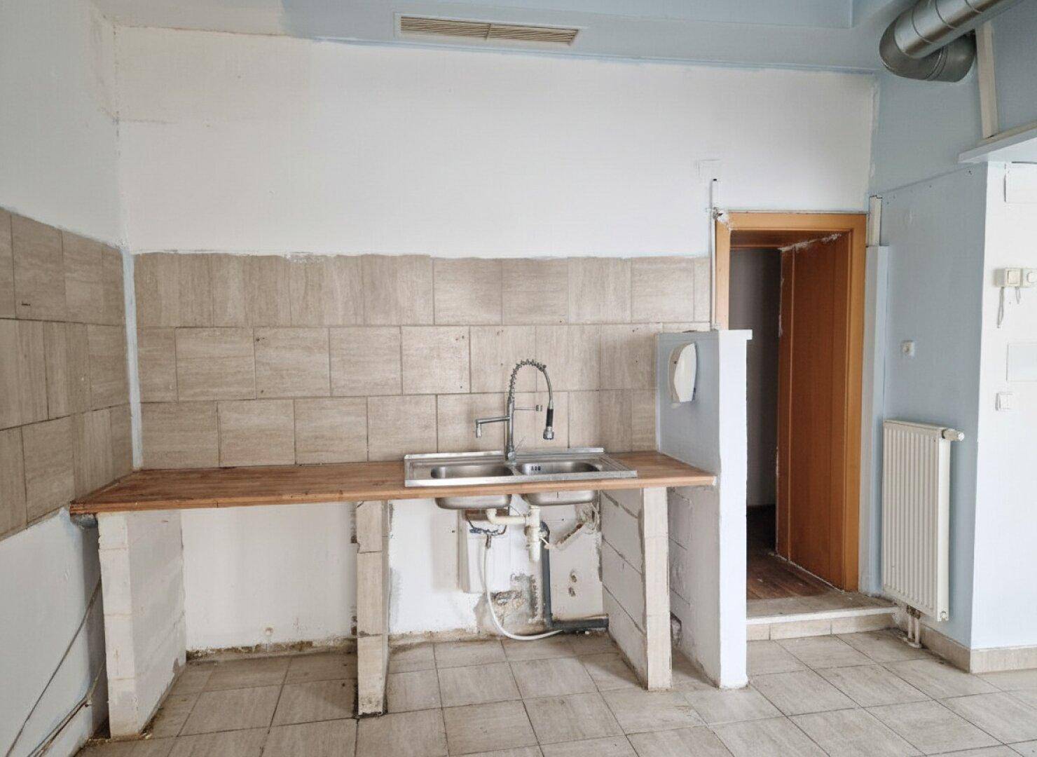 Detailansicht eines Spülbereichs in einer Gewerbeküche mit Doppelwaschbecken und Holztheke.