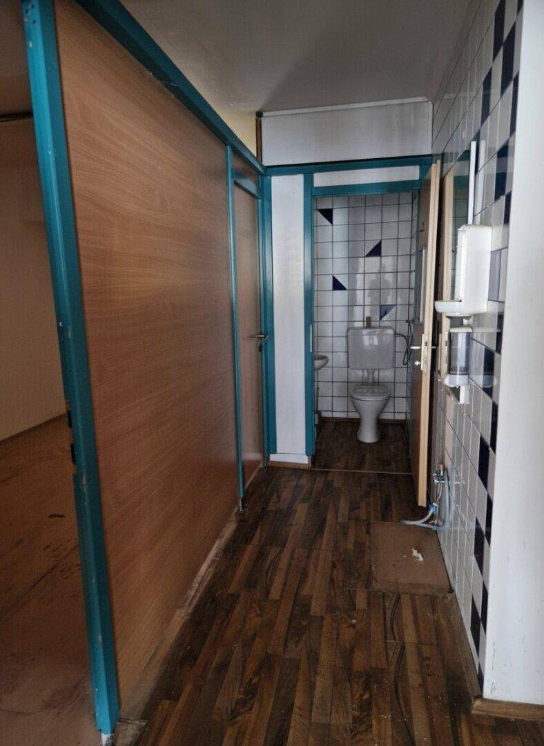 Flur mit Holzboden und Zugang zu einem Badezimmer mit blau-weiß gefliesten Wänden.