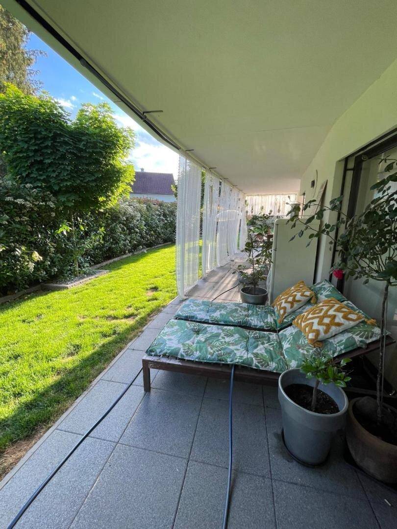 Überdachte Terrasse mit bequemen Sonnenliegen und direktem Zugang zum grünen Garten.