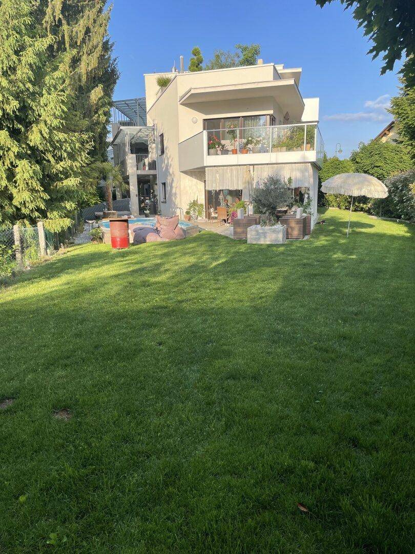 Moderne Architektur des Hauses mit mehreren Balkonen und großzügiger Gartenanlage.