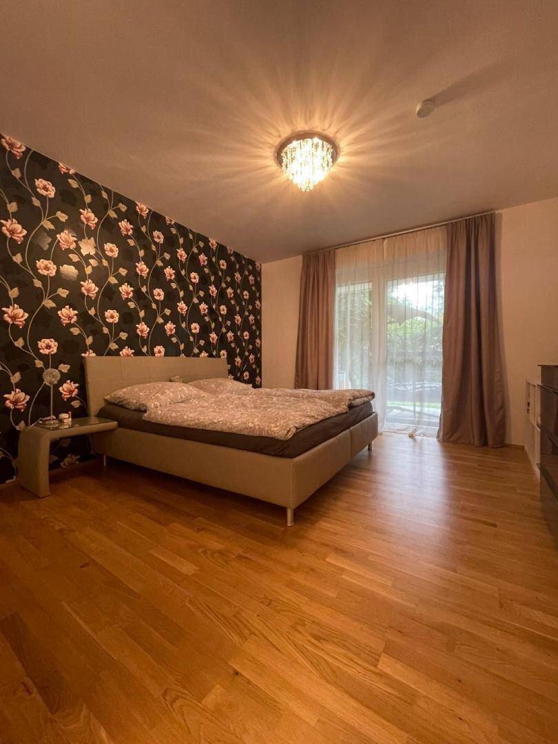 Gemütliches Schlafzimmer mit Doppelbett, Holzboden und einer stilvollen floralen Akzentwand.
