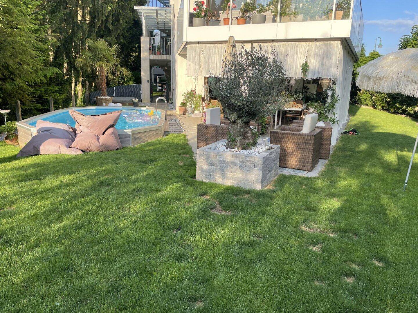Idyllischer Garten mit Rasenfläche, kleinem Pool und gemütlicher Sitzecke unter freiem Himmel.