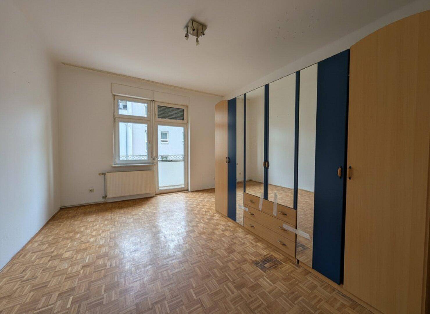Schlafzimmer mit Parkettboden und einem großen Spiegelschrank.