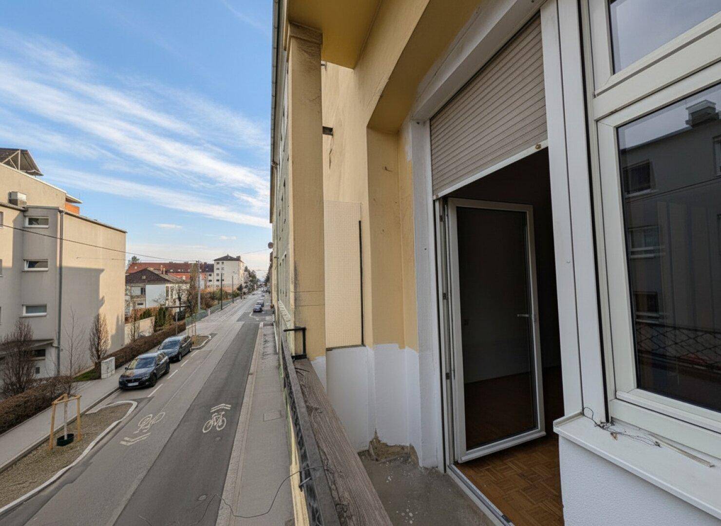 Blick vom Balkon entlang einer Wohnstraße mit parkenden Autos.