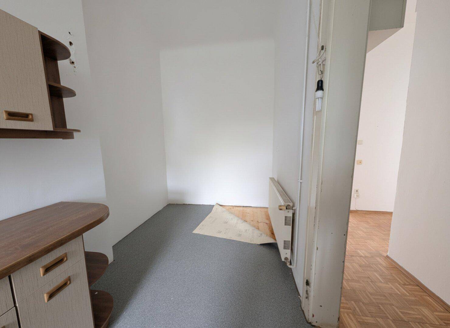 Kleiner Abstellraum mit einem Schrank und grauem Vinylboden.
