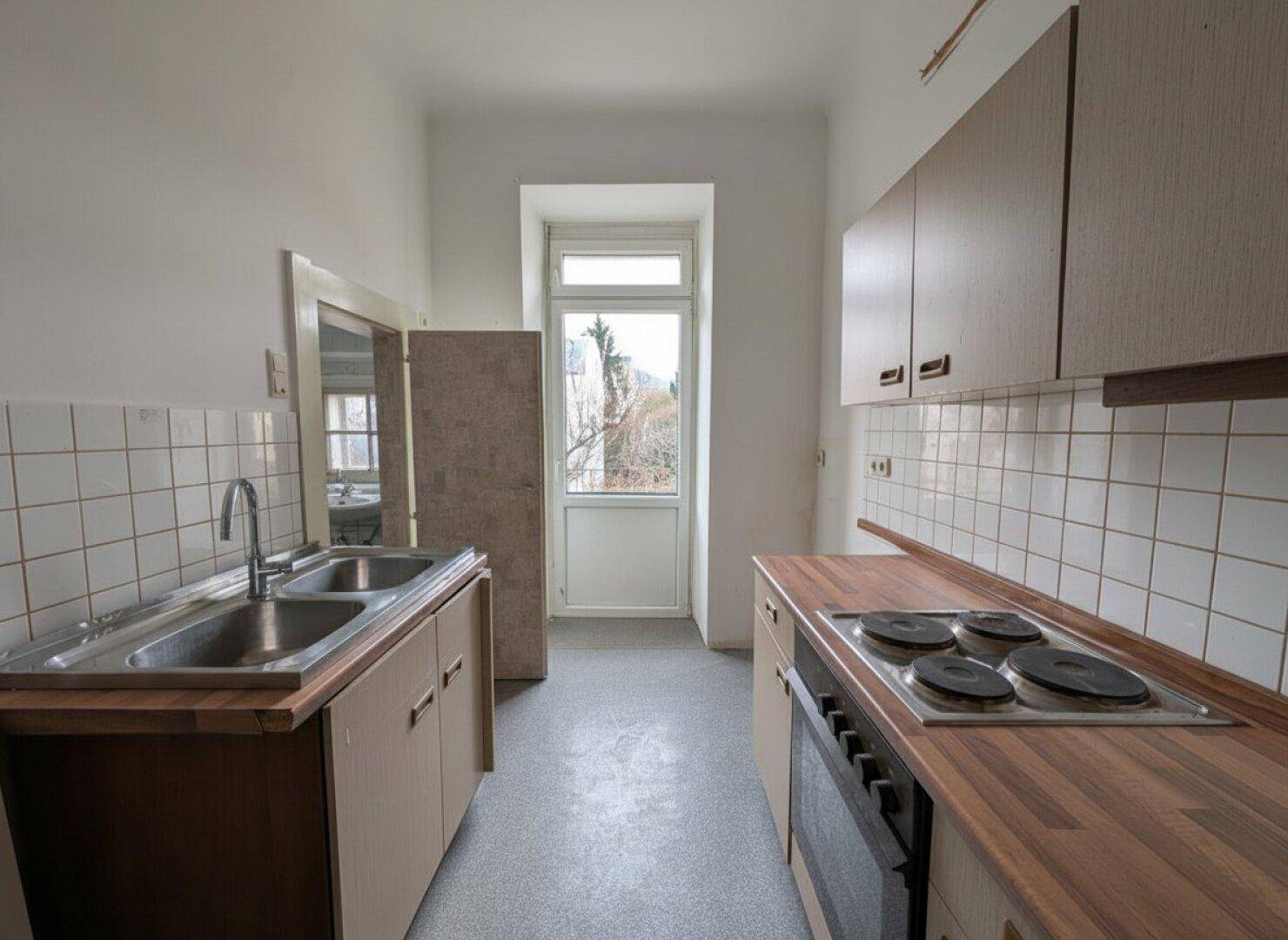 Küche mit Einbauküche, Spüle, Kochfeld und einem Fenster.