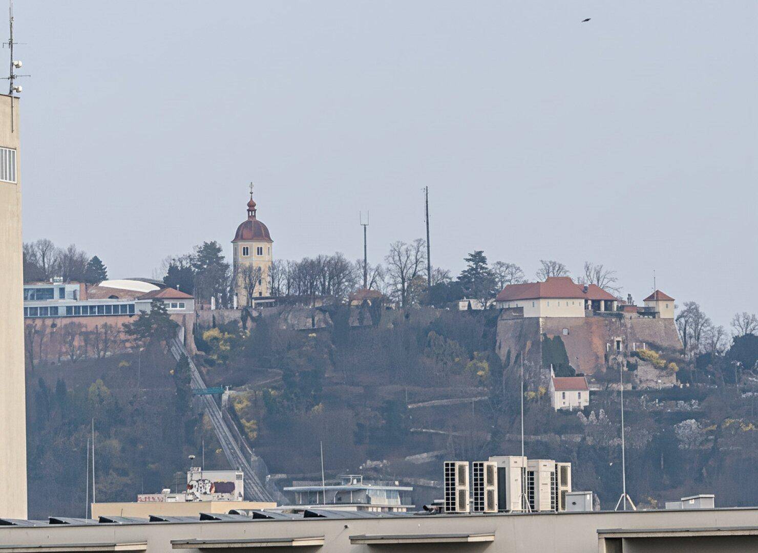 Panoramablick auf eine historische Festung auf einem Hügel und die umliegende Stadtlandschaft.