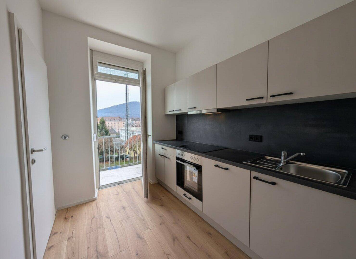 Moderne Küche mit Einbauschränken, Geräten und Zugang zu einem Balkon mit Bergblick.