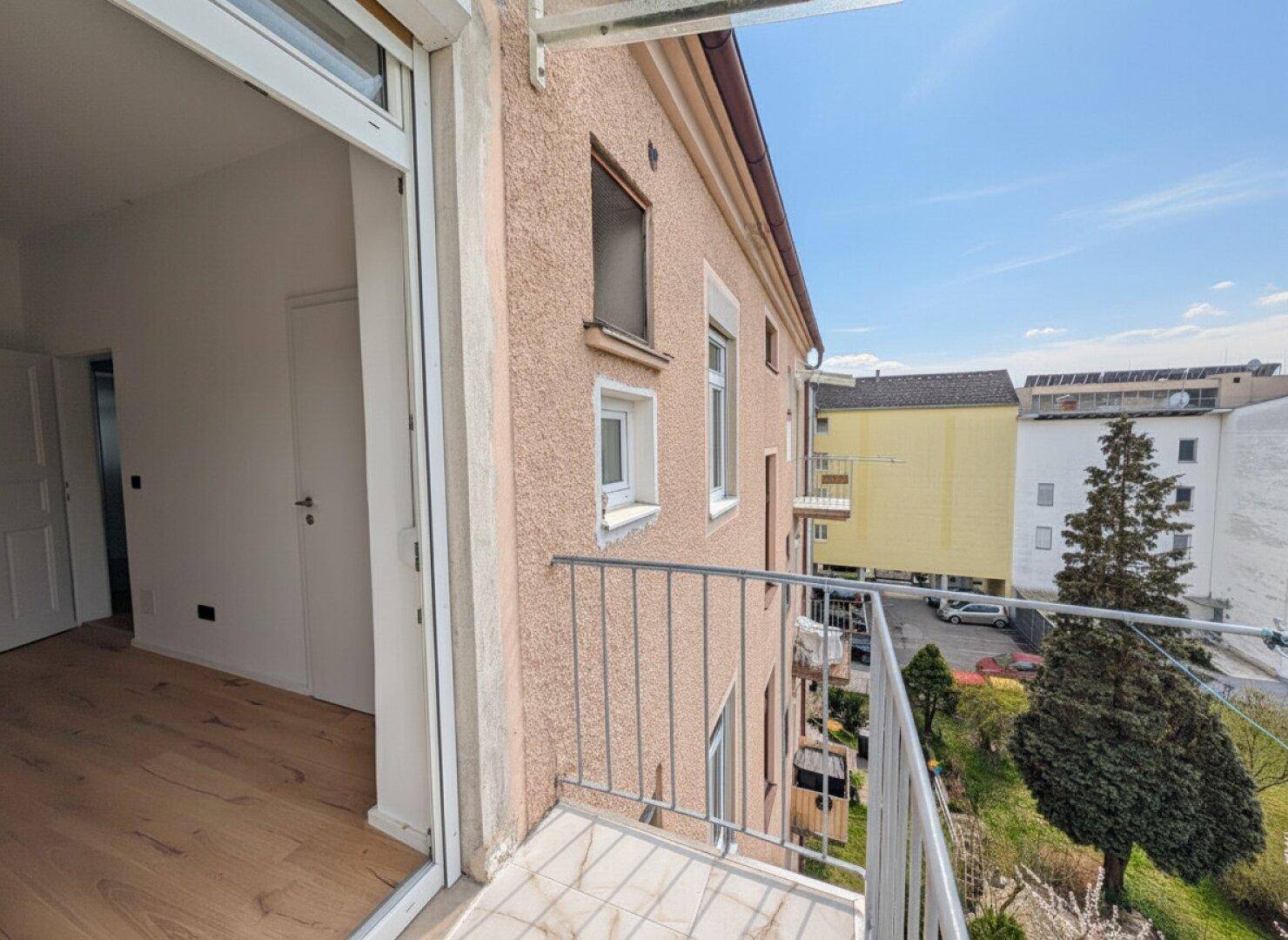 Seitlicher Blick auf einen Balkon mit Metallgeländer und die Fassade eines Wohngebäudes.