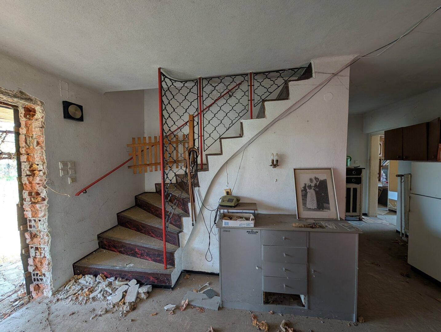 Treppenbereich mit altem Geländer und sichtbaren Abnutzungsspuren, der eine umfassende Renovierung erfordert.
