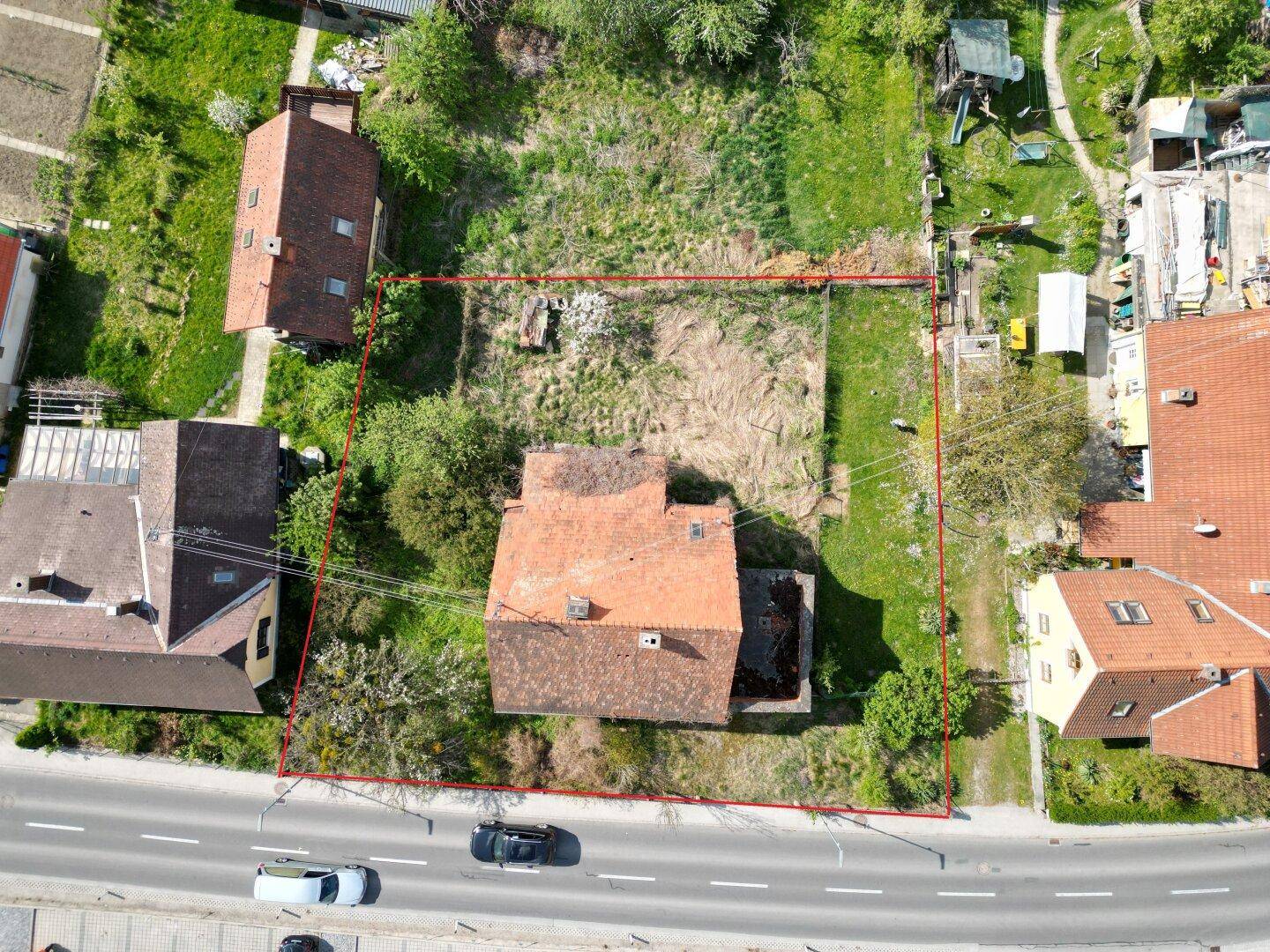 Luftaufnahme eines Grundstücks mit einem älteren Haus und rotem Umriss, der die Grundstücksgrenzen markiert.