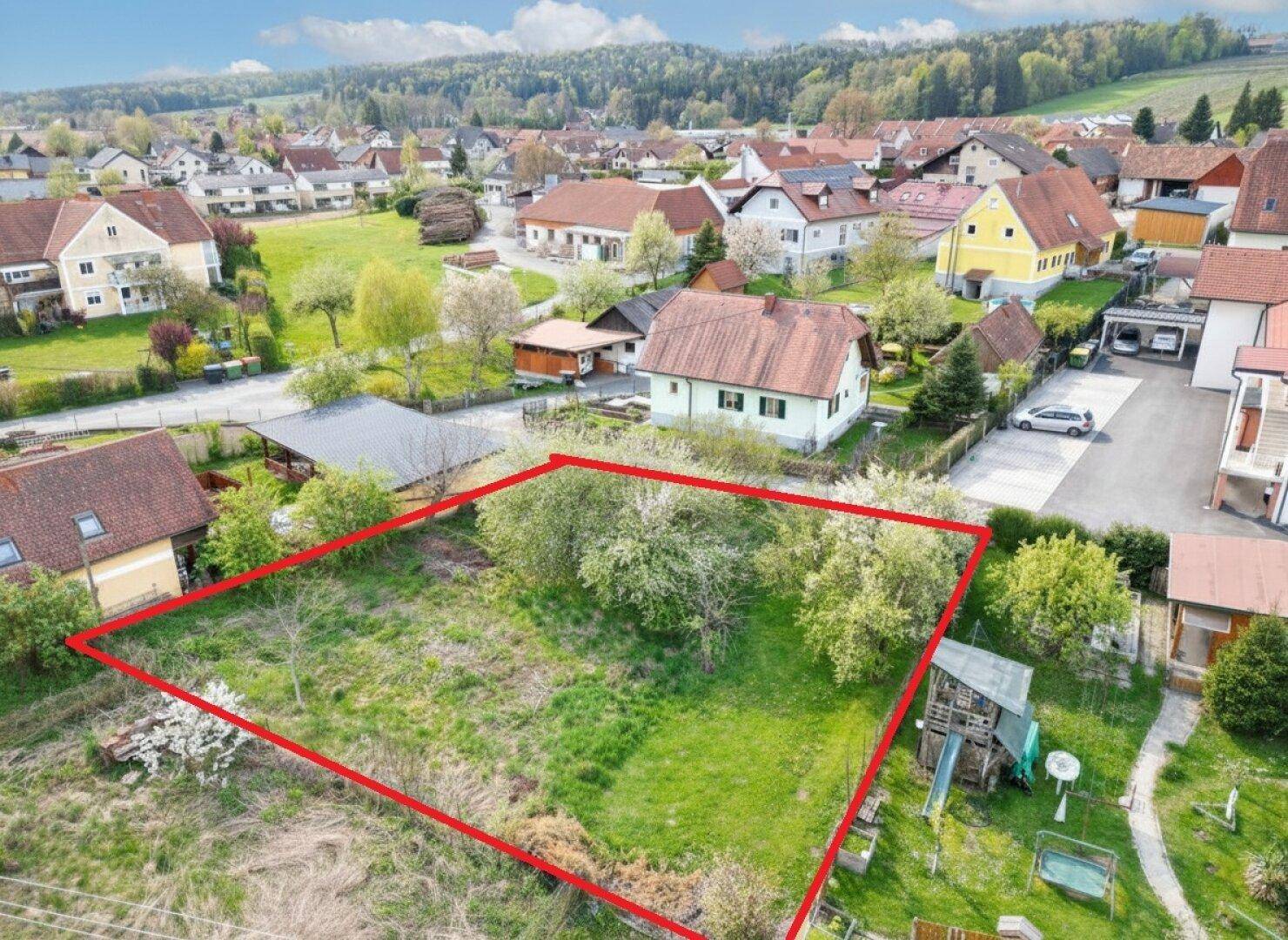 Luftaufnahme eines Baugrundstücks mit roter Umrandung in ländlicher Umgebung.