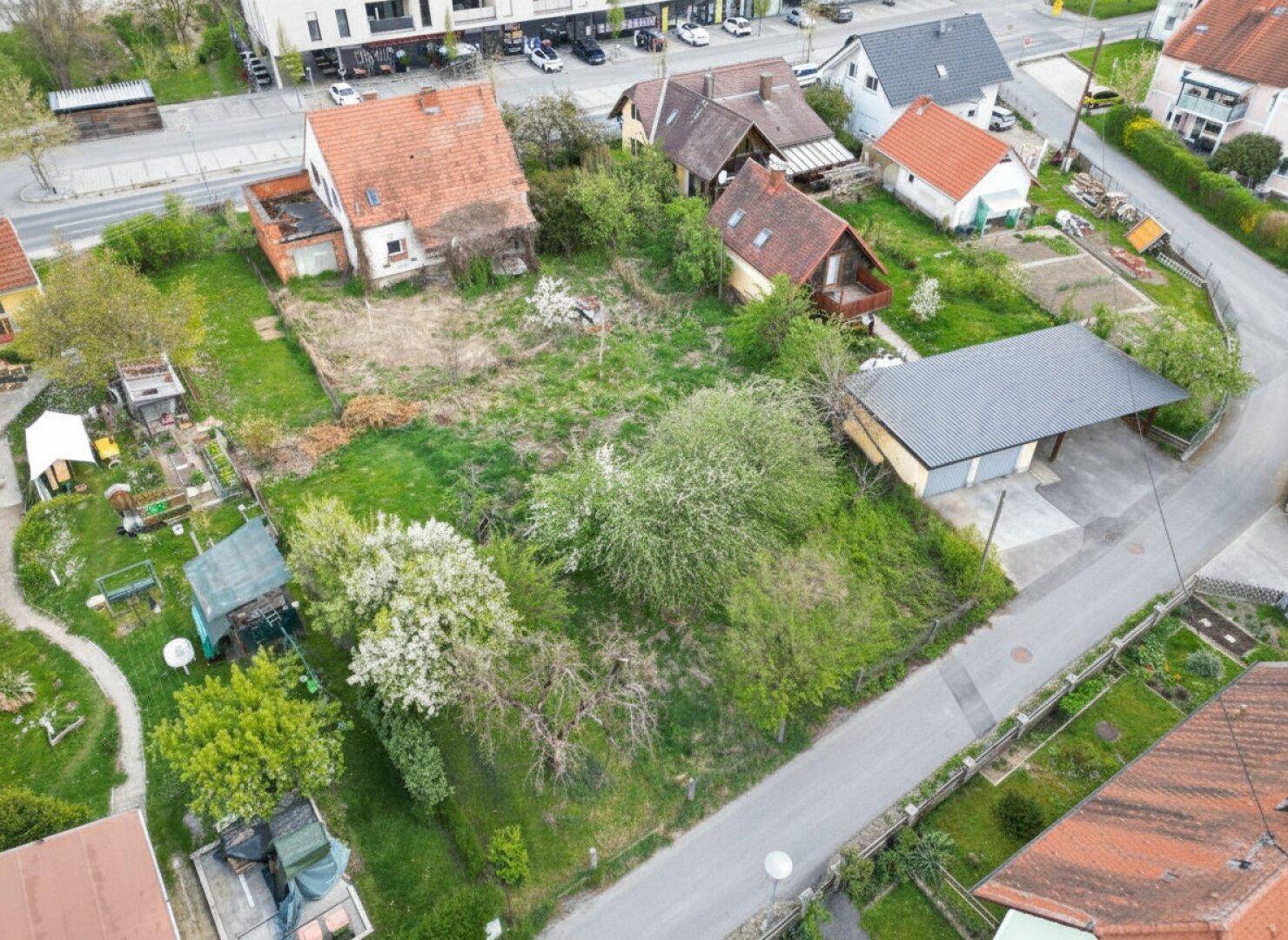 Luftaufnahme des Baugrundstücks mit angrenzenden Gebäuden und einer Zufahrtsstraße.