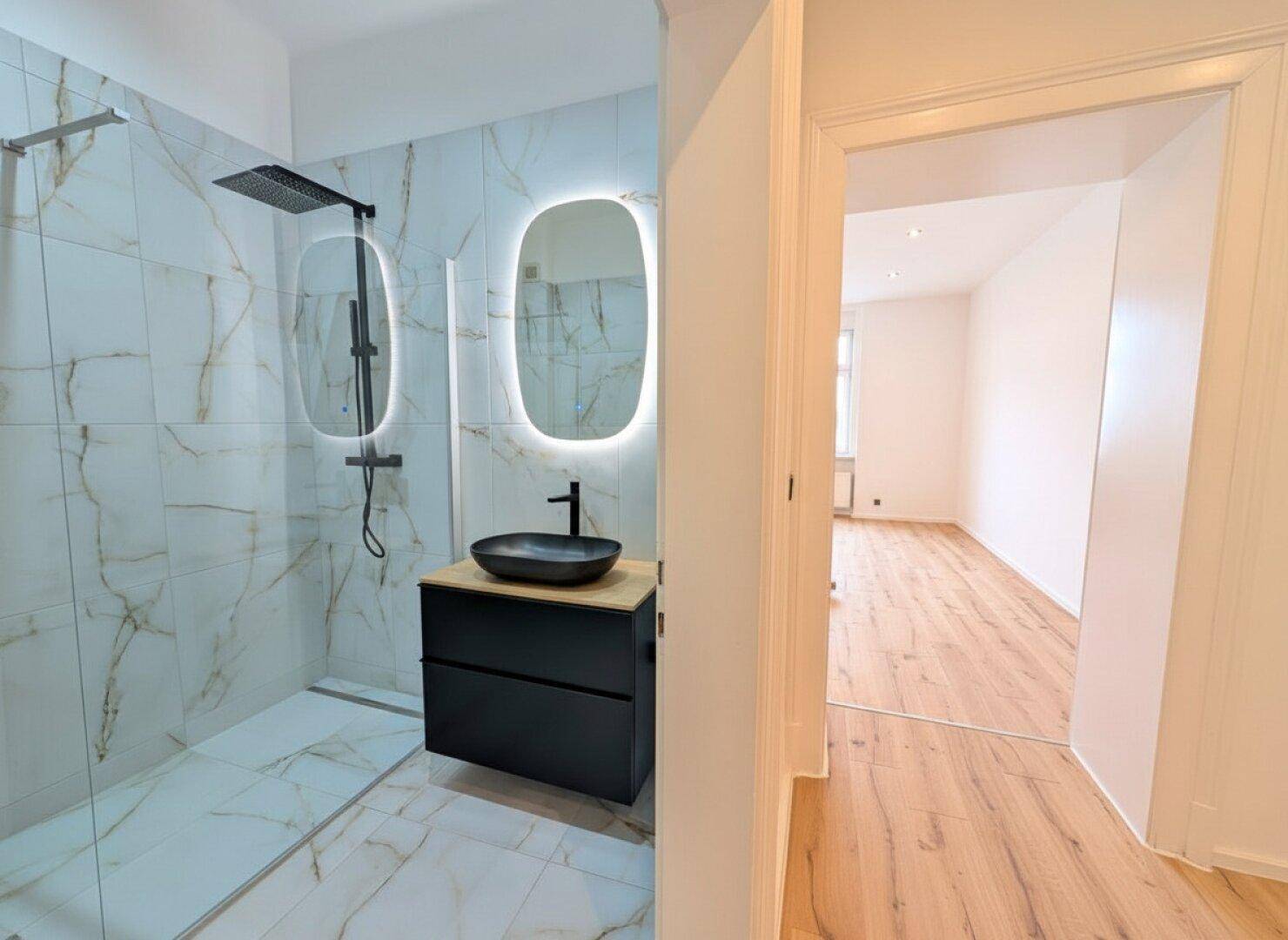 Modernes Badezimmer mit begehbarer Dusche, eleganten Marmorfliesen und stilvollem Waschtisch.