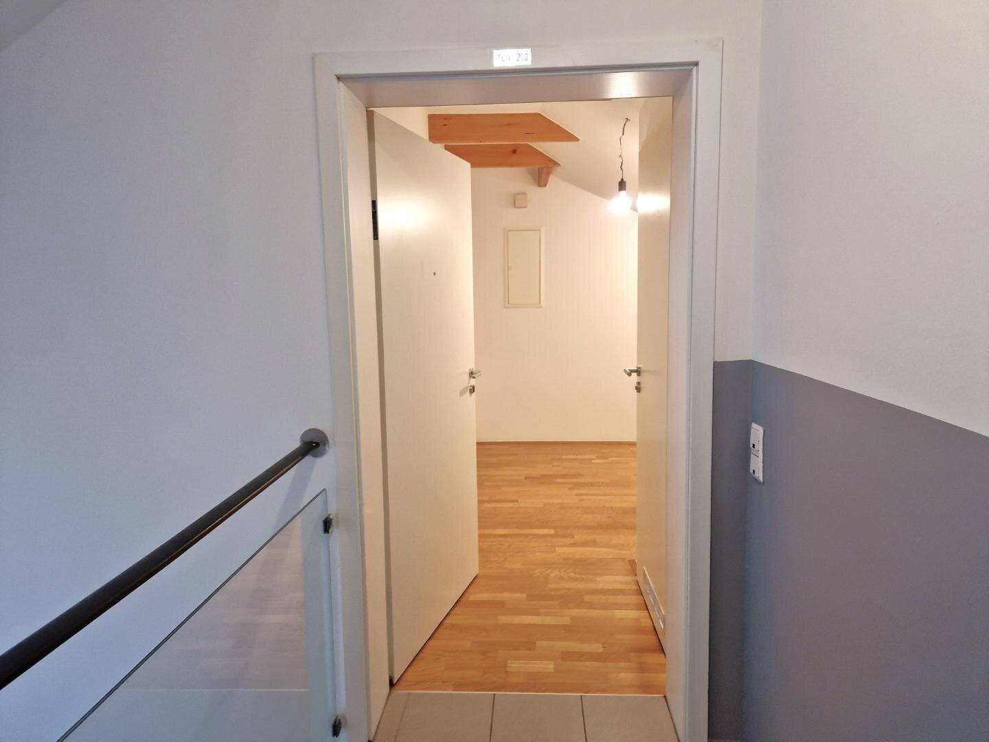 Heller Flurbereich mit Holzboden und Blick in ein weiteres Zimmer im Dachgeschoss.