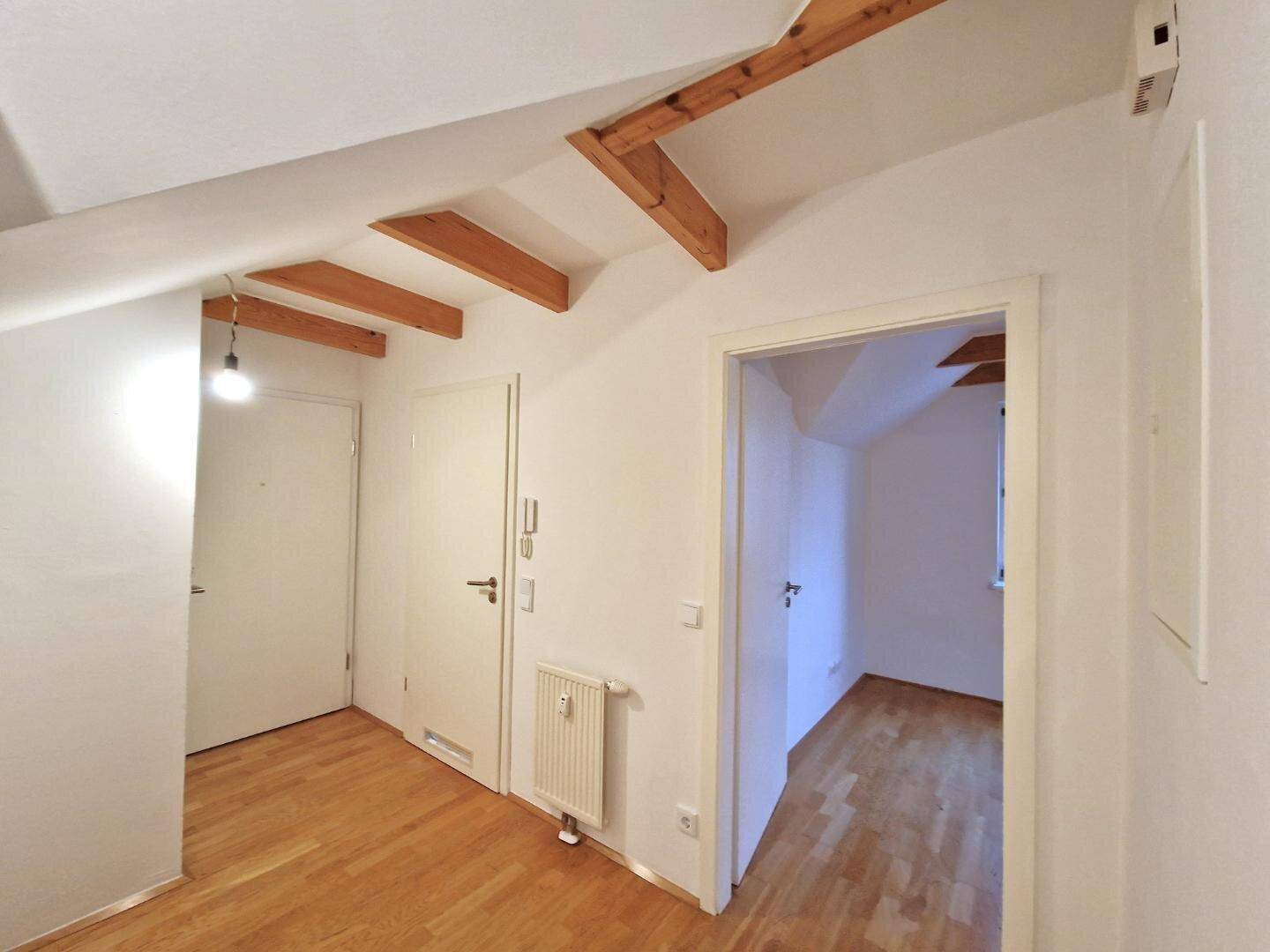Heller Flur mit Holzbalken, Parkettboden und Zugang zu weiteren Zimmern im Dachgeschoss.