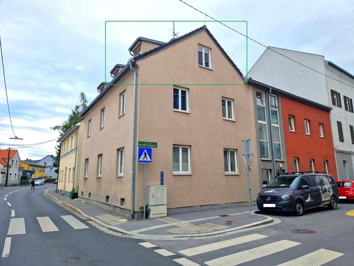 Mehrstöckiges Gebäude an einer Straßenecke mit klassischer Fassade und Satteldach.