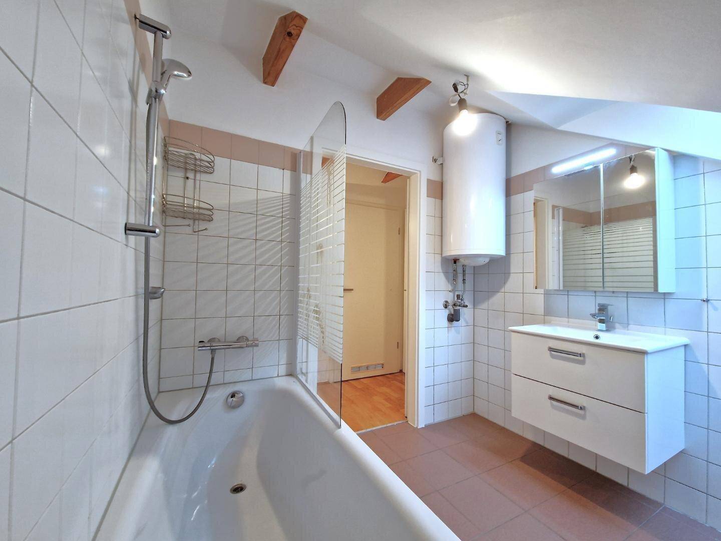Badezimmer im Dachgeschoss mit Badewanne, Dusche, Waschbecken und praktischem Spiegelschrank.