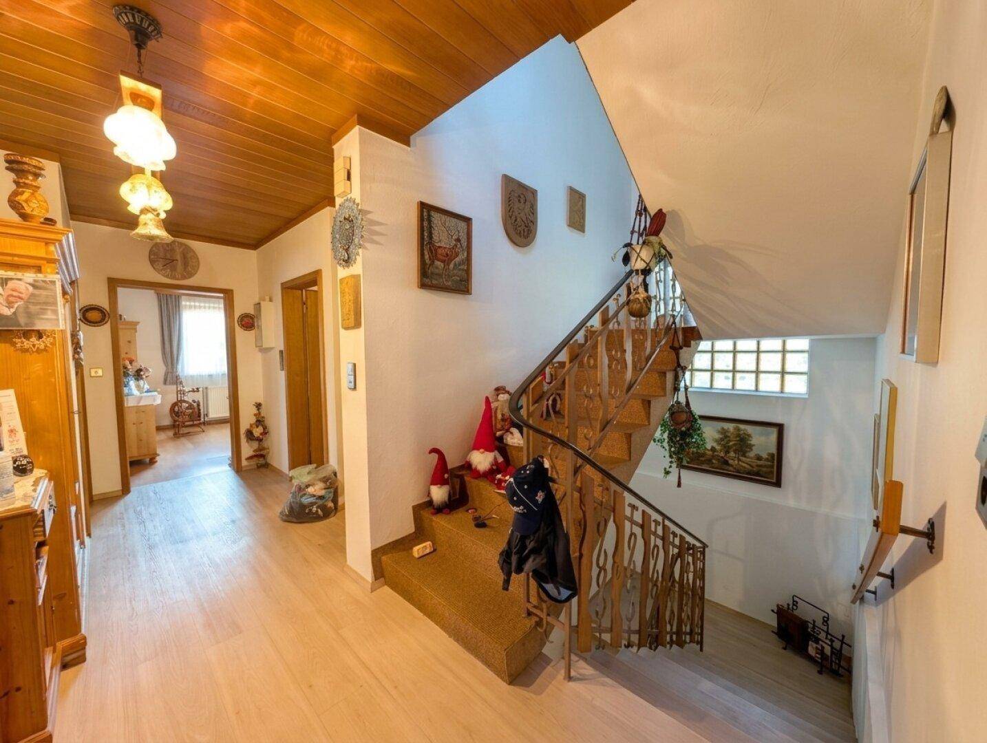 Gemütlicher Flur mit Holztreppe, Teppichstufen und traditioneller Dekoration.