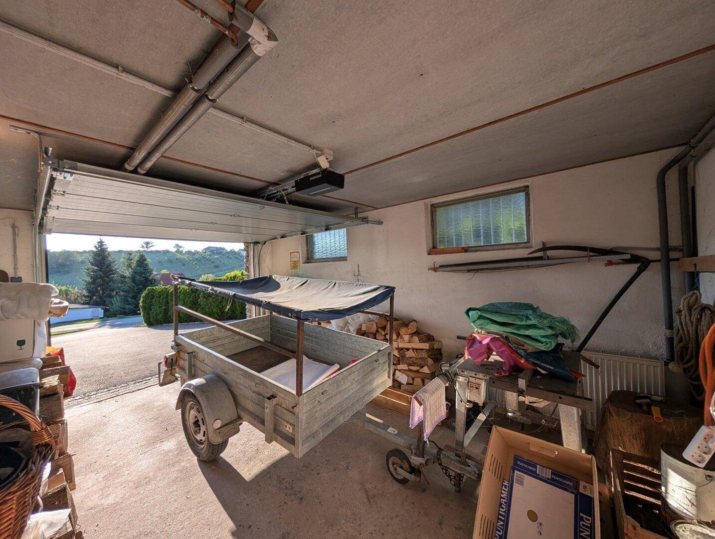 Geräumige Garage mit offenem Tor, bietet Platz für Fahrzeuge und Lagerung.