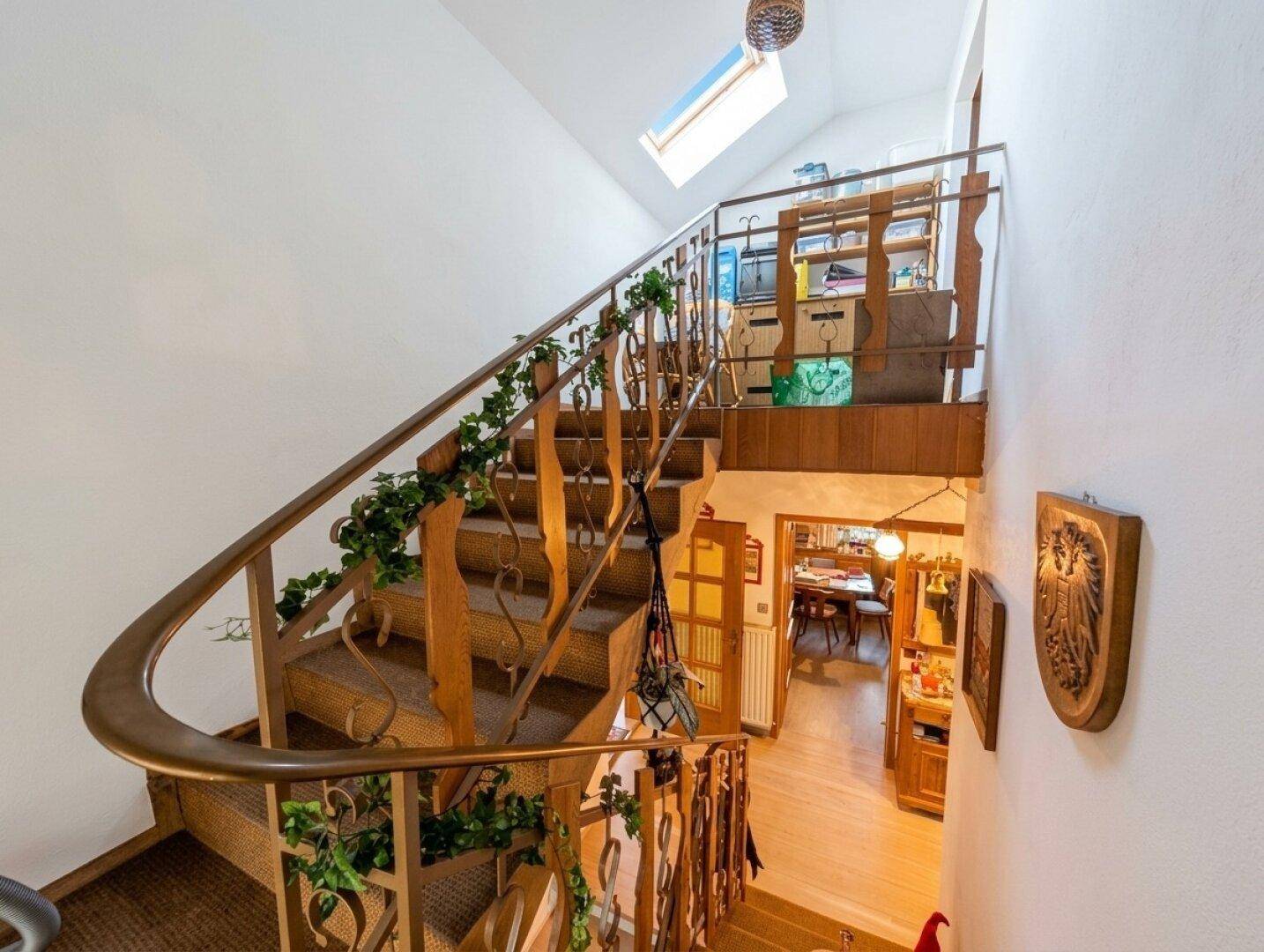 Traditionelles Treppenhaus mit Holzgeländer, Teppichstufen und Oberlicht für natürliches Licht.