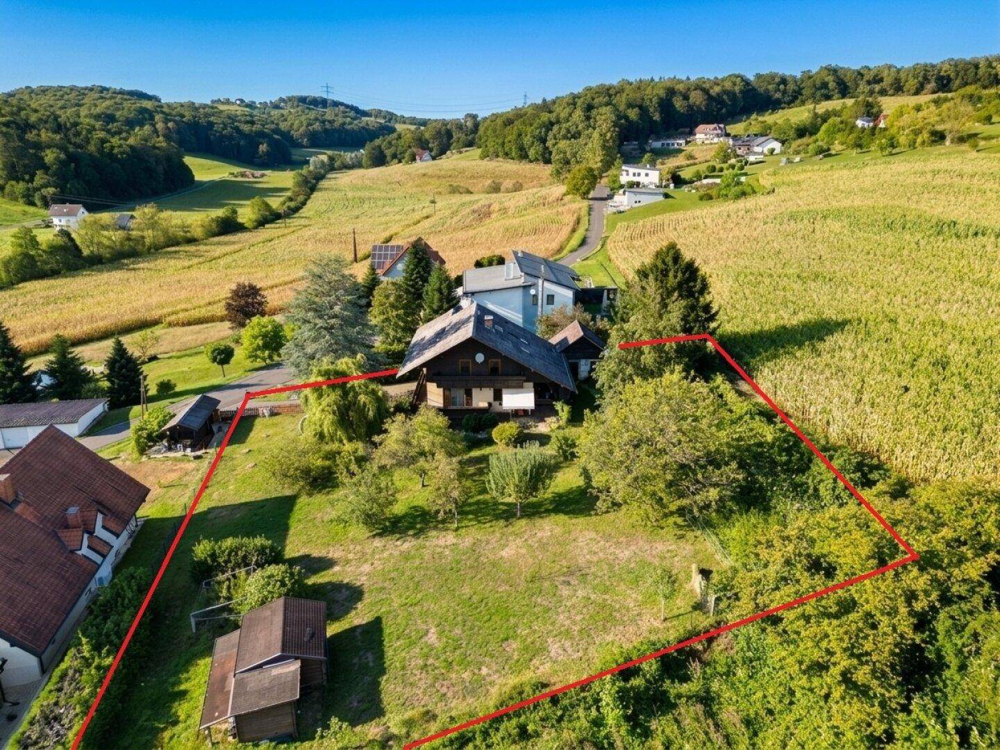Luftaufnahme eines Anwesens mit großem Grundstück, umgeben von grüner Landschaft.