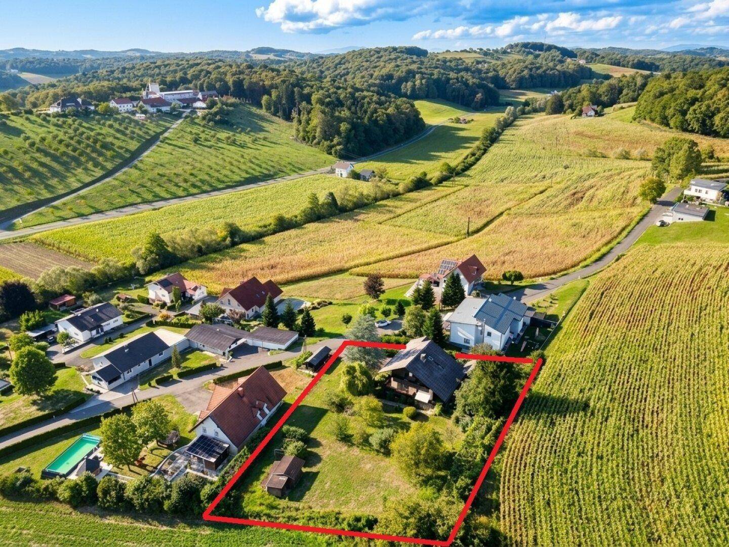 Weitläufige Luftaufnahme des Anwesens in einer idyllischen Hügellandschaft mit umliegenden Feldern.