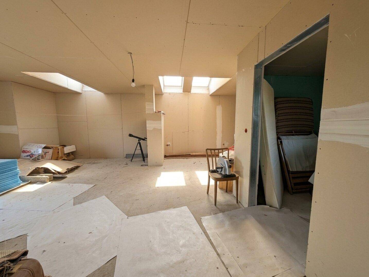 Heller, unfertiger Dachgeschossraum mit mehreren Dachfenstern für viel Tageslicht.