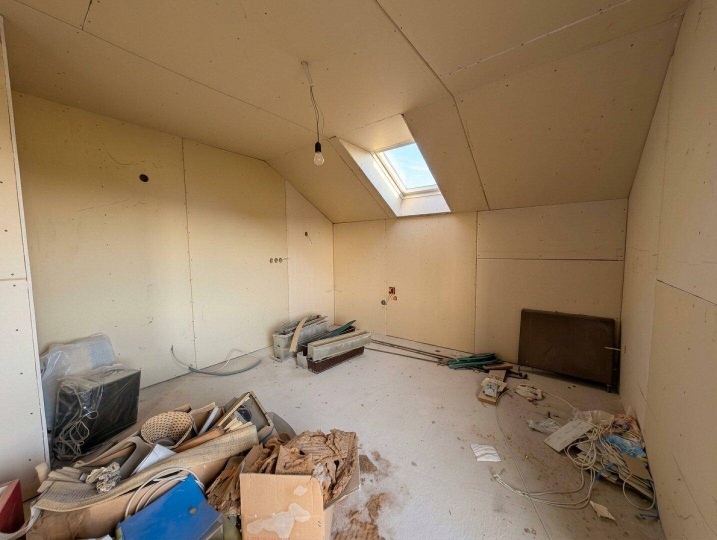 Kleinerer unfertiger Dachgeschossraum mit einem Dachfenster, ideal für ein zukünftiges Zimmer.