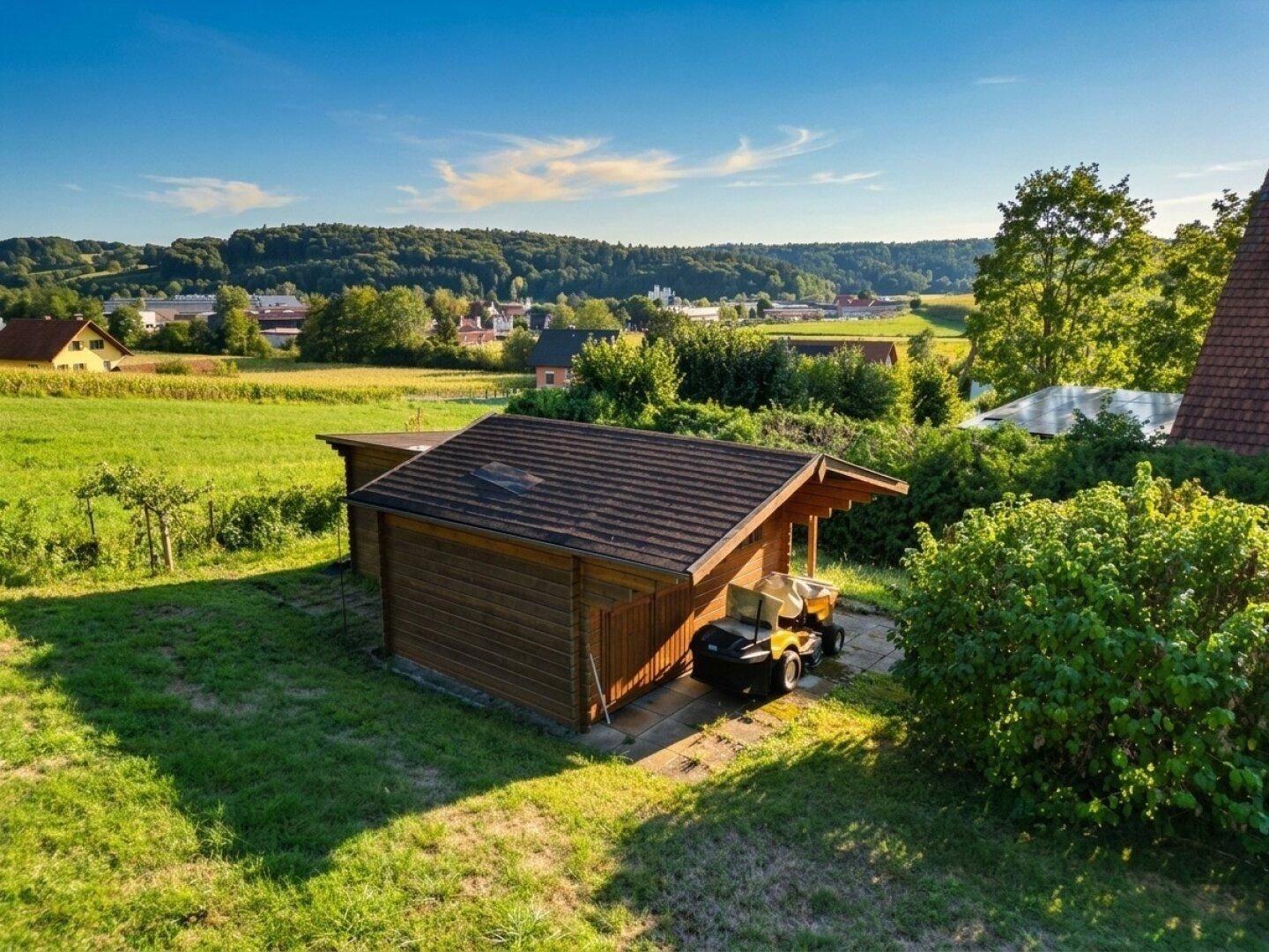 Rustikales Gartenhaus aus Holz mit Vordach, umgeben von grüner Natur.