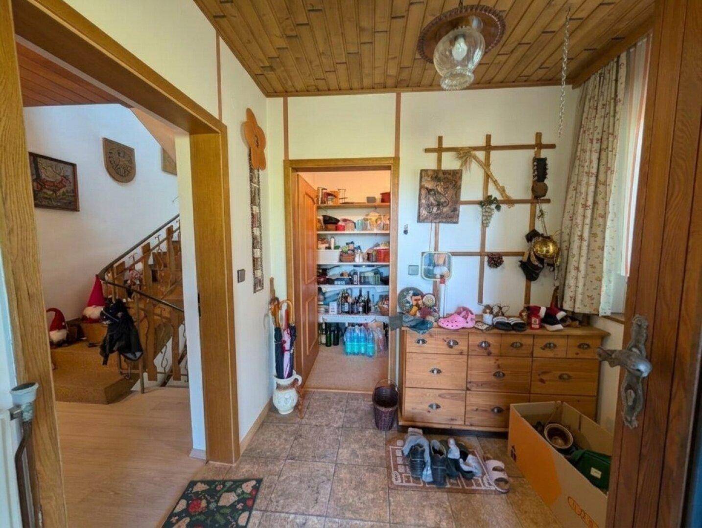 Gemütlicher Flur mit Holzdecke, Fliesenboden und Zugang zu einer gut gefüllten Speisekammer.