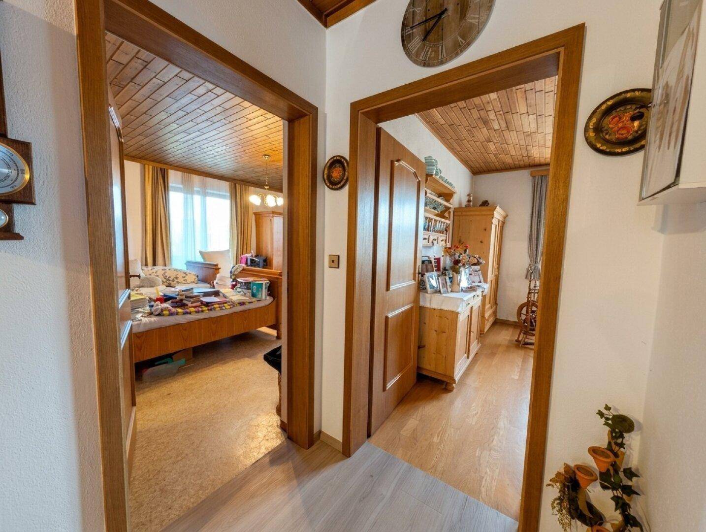 Heller Flur mit Holzdecke, der zu zwei Schlafzimmern mit traditionellen Holzmöbeln führt.