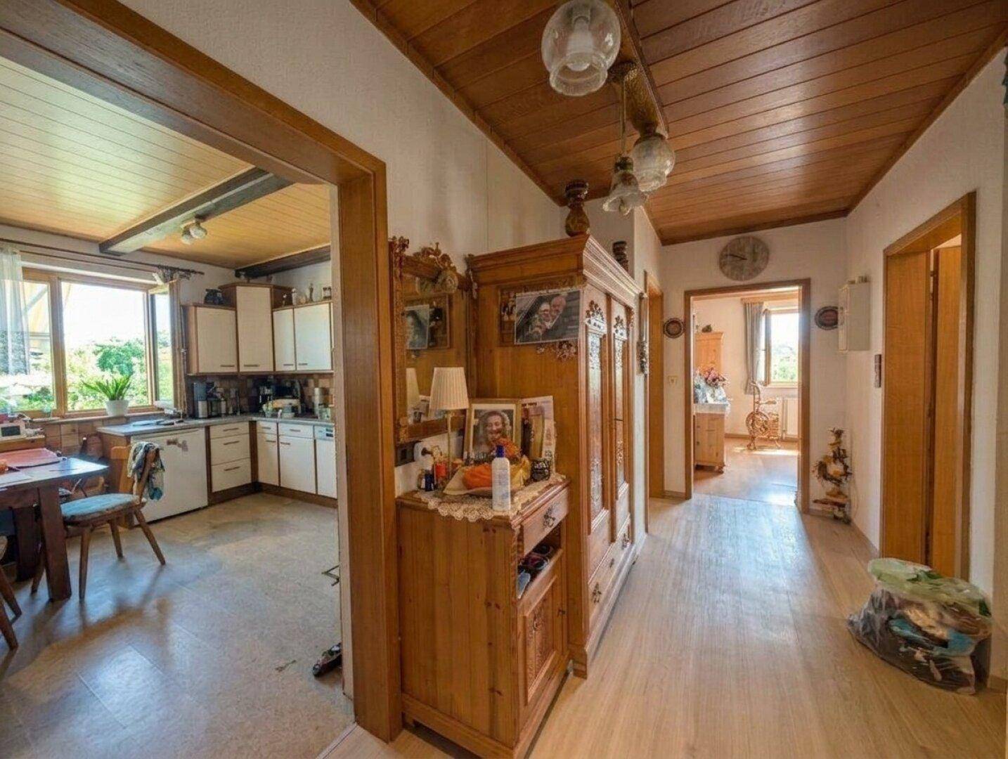 Langer Flur mit Holzdecke und traditionellen Möbeln, der zu einer Küche und weiteren Räumen führt.