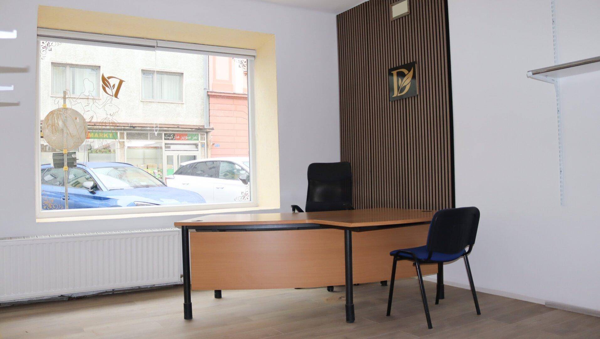 Büroraum mit einem Schreibtisch und Blick auf die Straße durch ein großes Fenster.