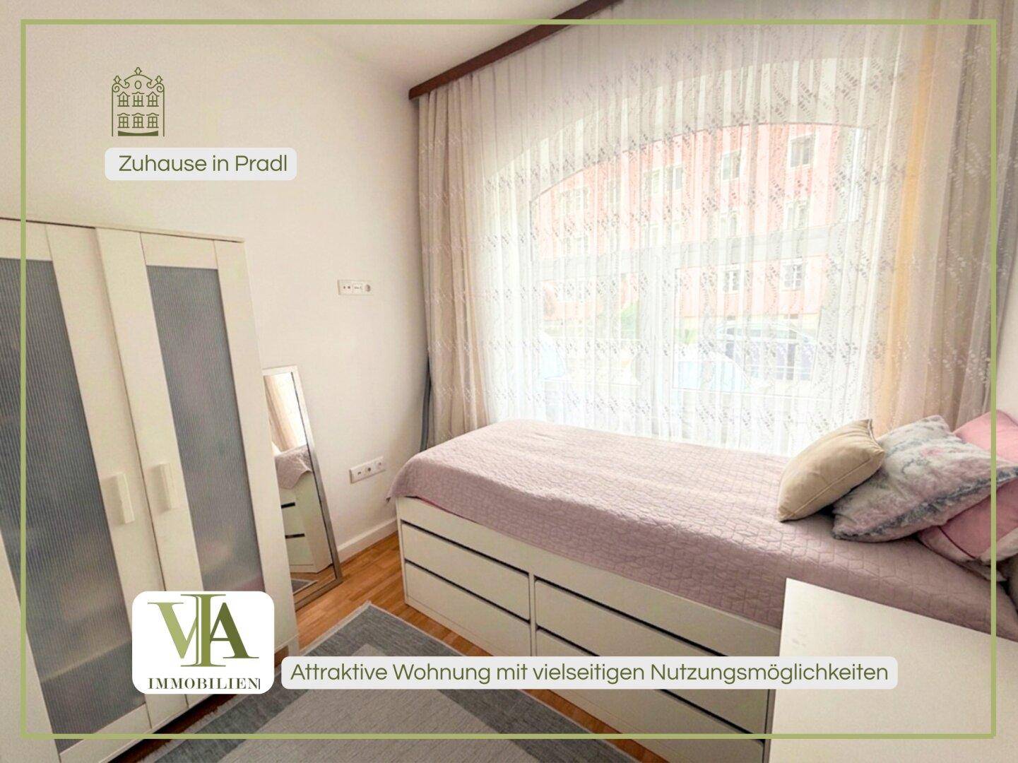 Helles Schlafzimmer mit Bett, Kleiderschrank und großem Fenster.