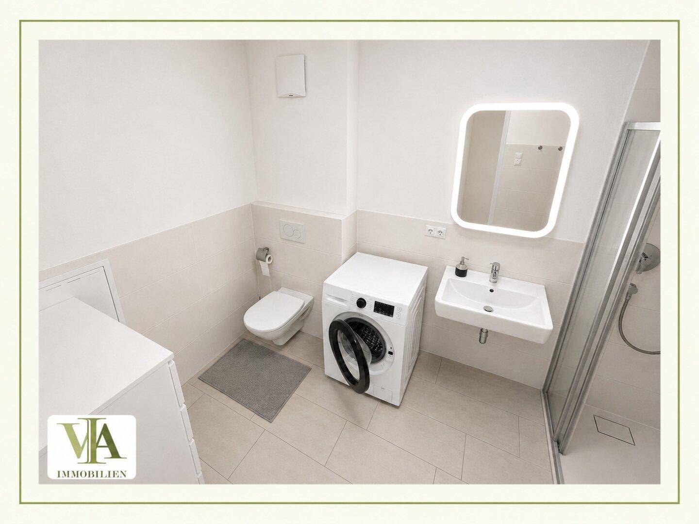 Helles Badezimmer mit Duschkabine, Waschbecken und praktischer Waschmaschine.