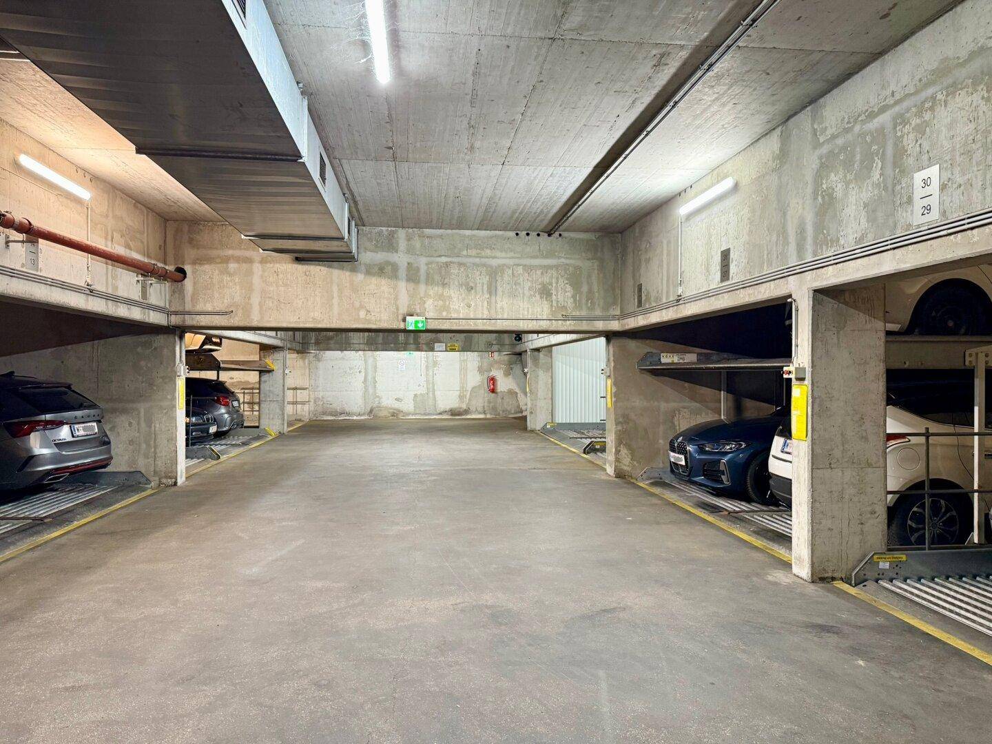 Geräumige Tiefgarage mit mehreren Doppelparkern und Betonarchitektur.