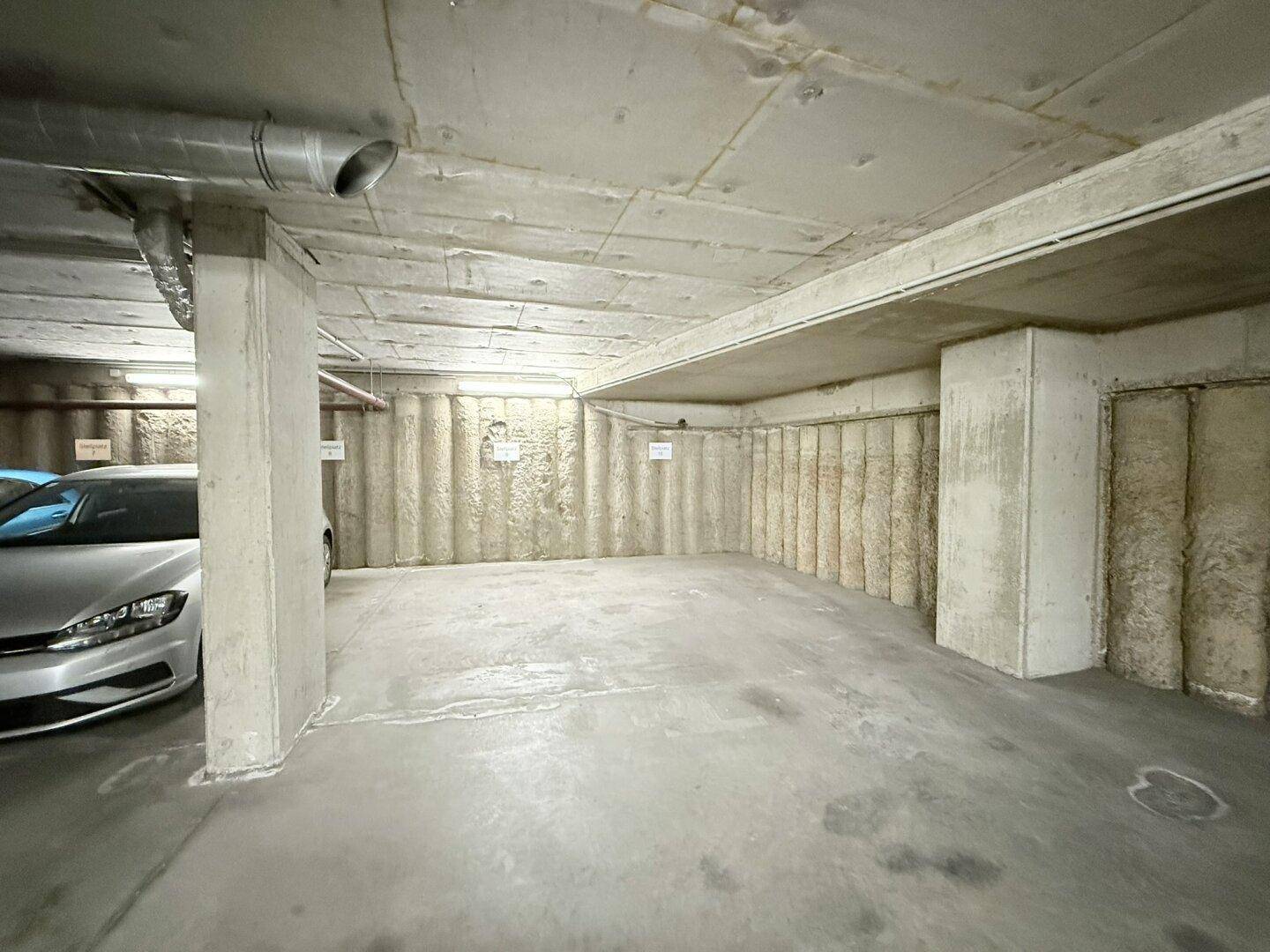 Einzelner Stellplatz in der Tiefgarage mit isolierten Wänden und robustem Betonboden.