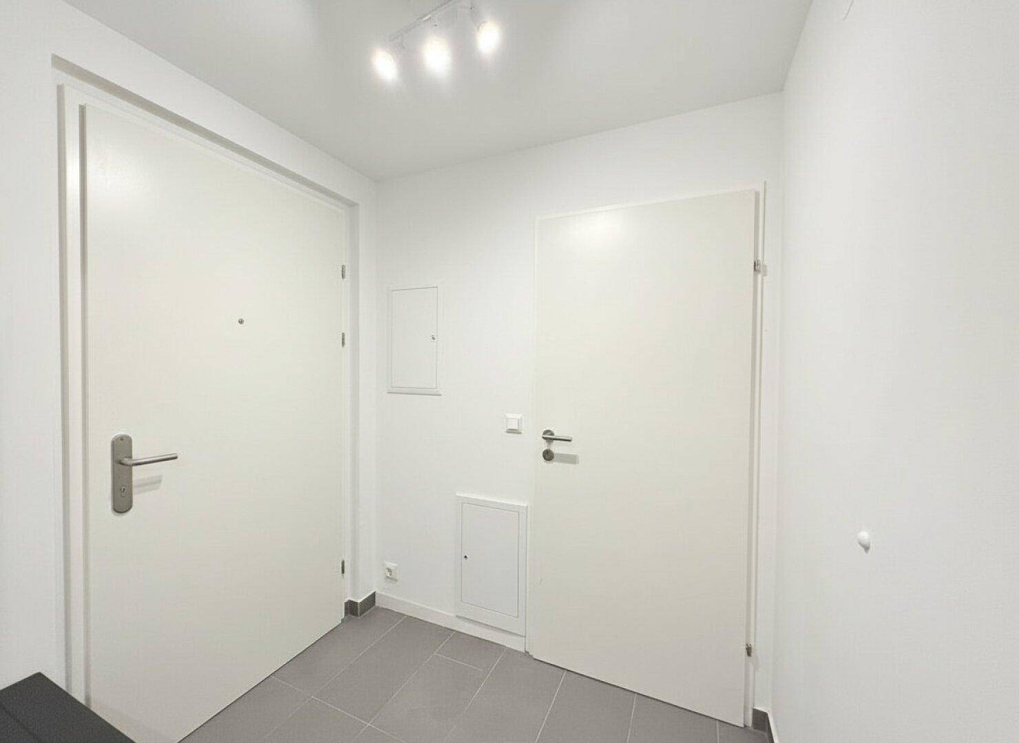 Eingangsbereich mit Fliesenboden und zwei Türen, bietet Zugang zur Wohnung.