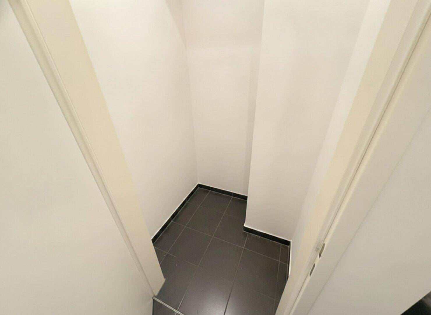Kleiner, leerer Abstellraum mit dunklem Fliesenboden, ideal für zusätzlichen Stauraum.