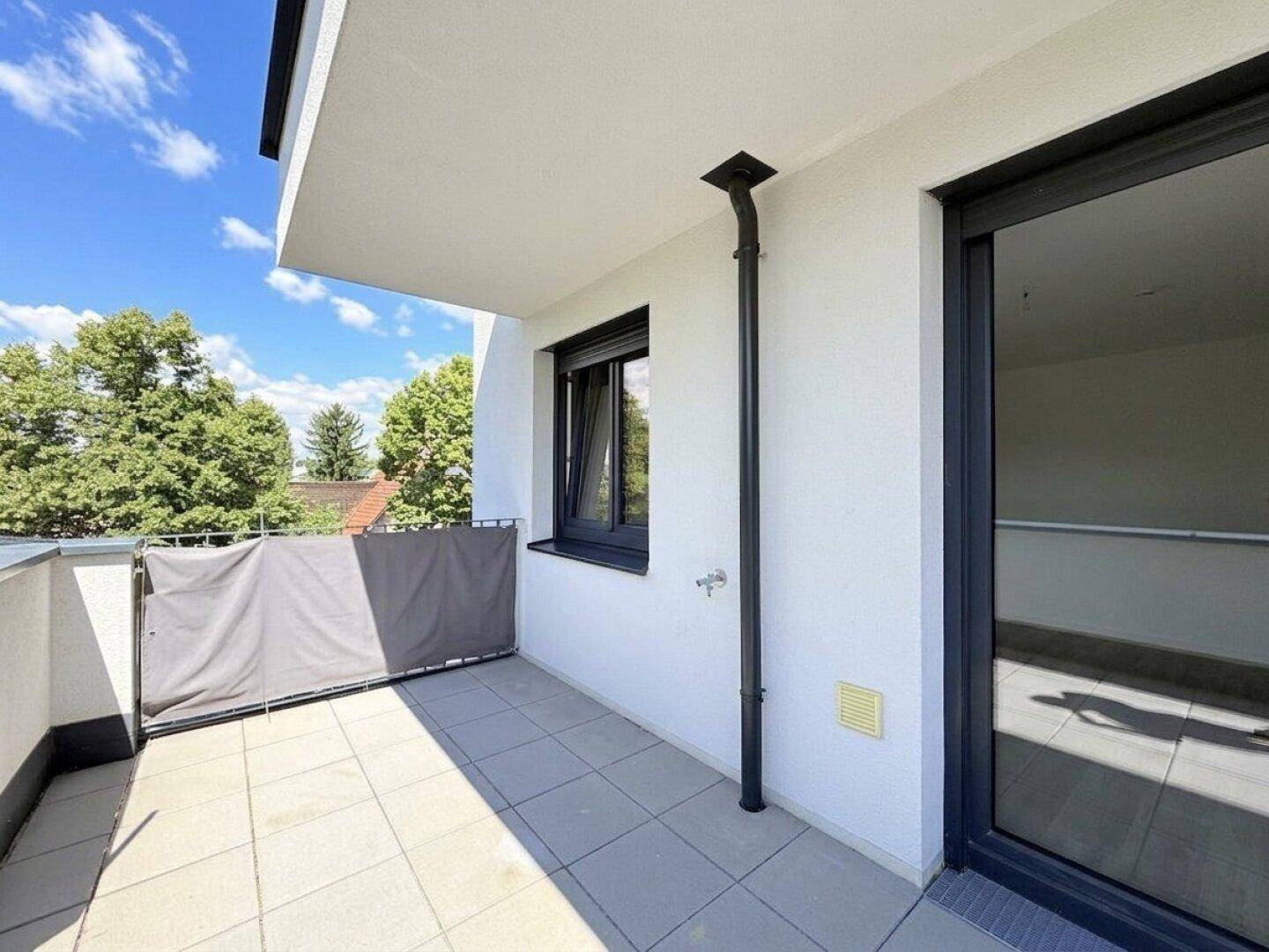 Moderner Balkon mit Fliesenboden und schützender Brüstung, bietet einen angenehmen Außenbereich.