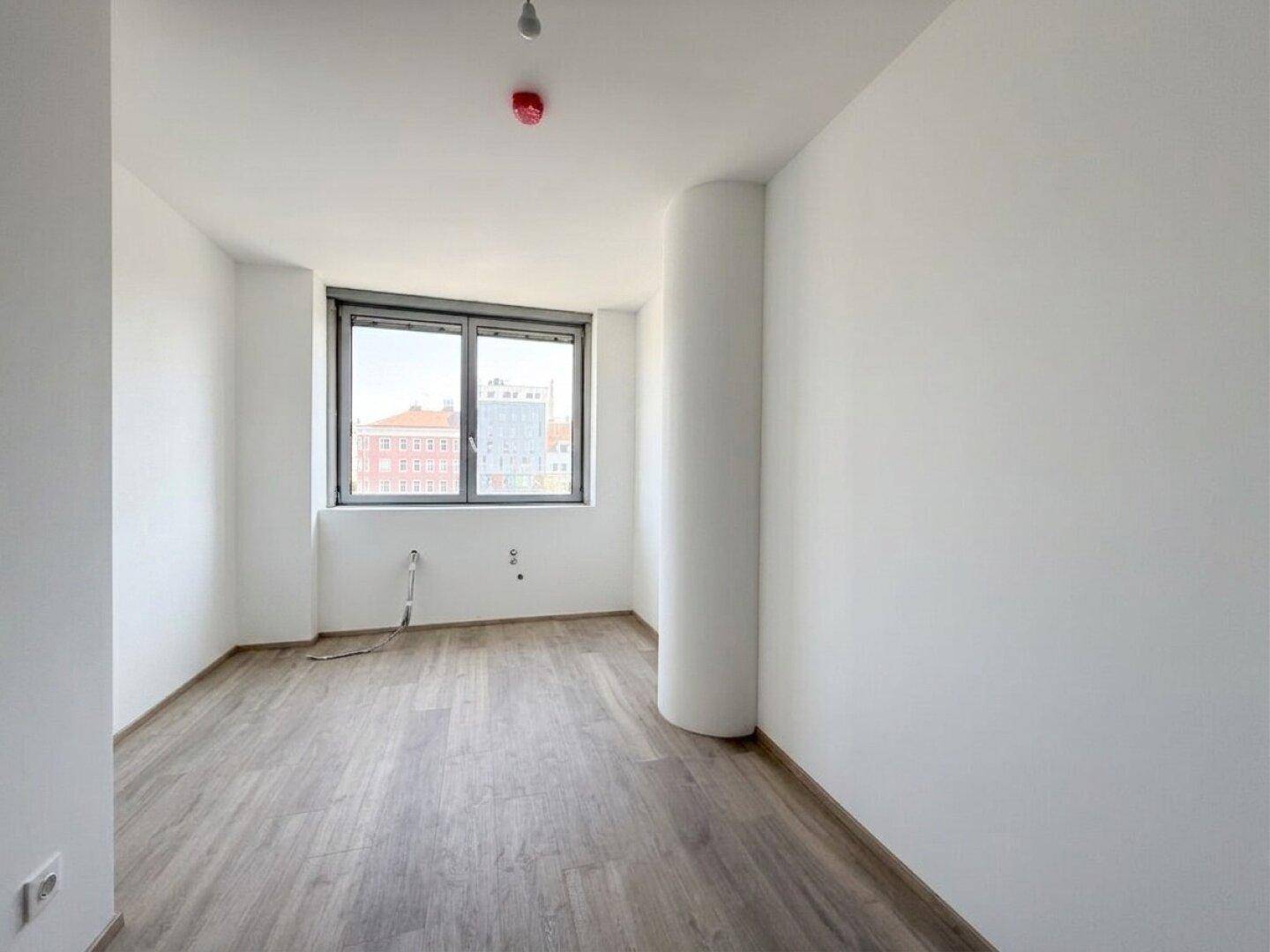 Lichtdurchfluteter Raum mit Laminatboden und einem großen Fenster, bietet vielseitige Nutzungsmöglichkeiten.