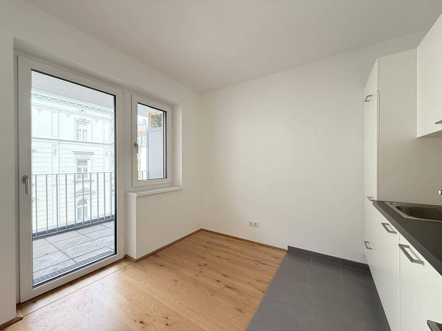 Küchenbereich mit Holzboden und Fliesen, direktem Zugang zum Balkon und Stadtblick.