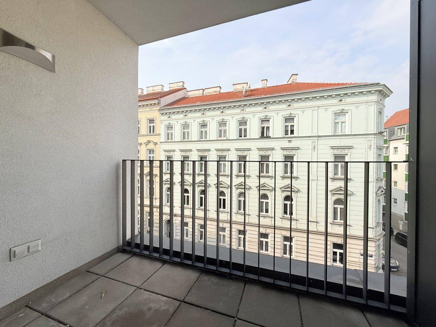 Balkon mit Metallgeländer und Blick auf die historische Architektur der gegenüberliegenden Gebäude.