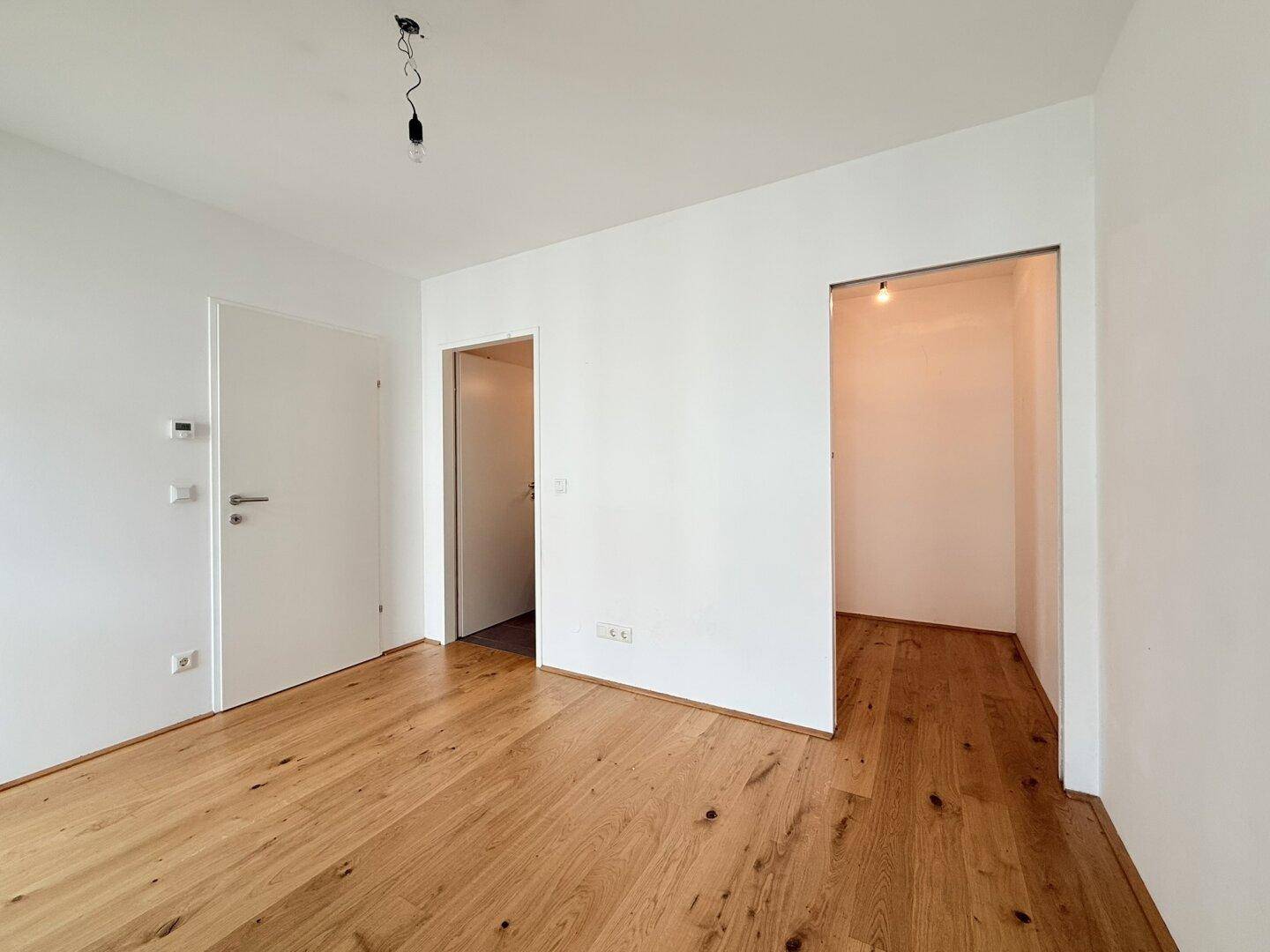 Heller Flur mit Holzboden und Zugang zu verschiedenen Räumen der Wohnung.