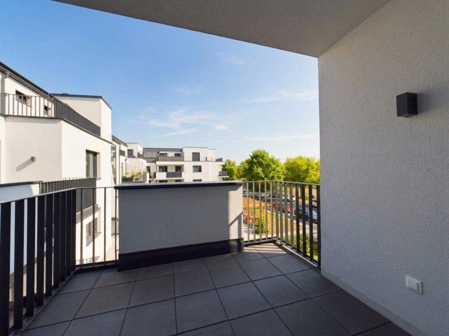 Geräumiger Balkon mit Fliesenboden und weitem Blick auf die grüne Umgebung.